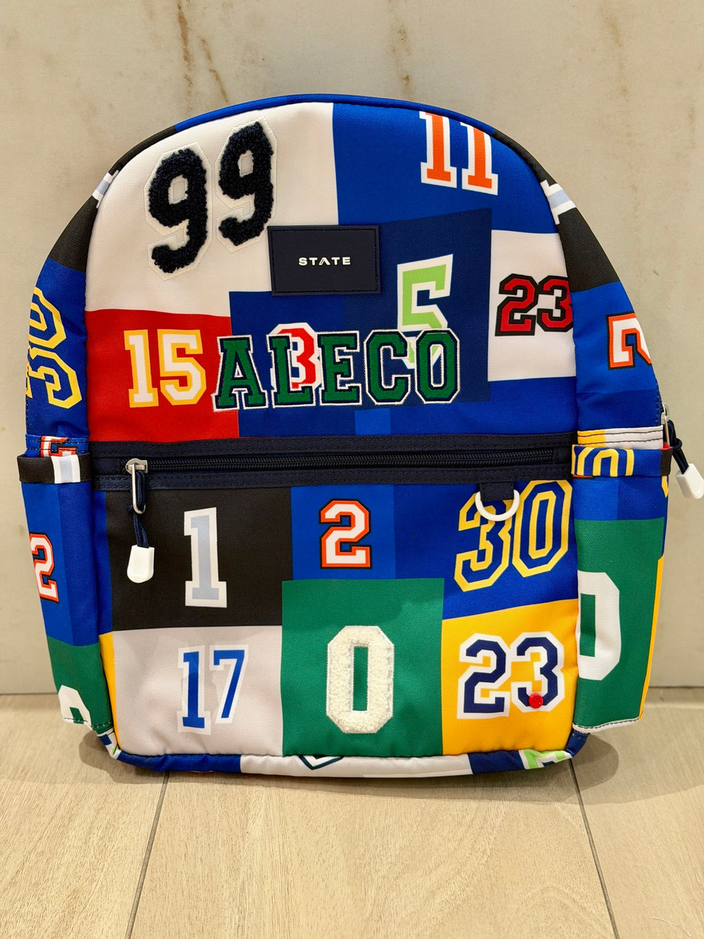 Sports numbers print kids backpack with the name Aleco custom embroidered in green varsity letters