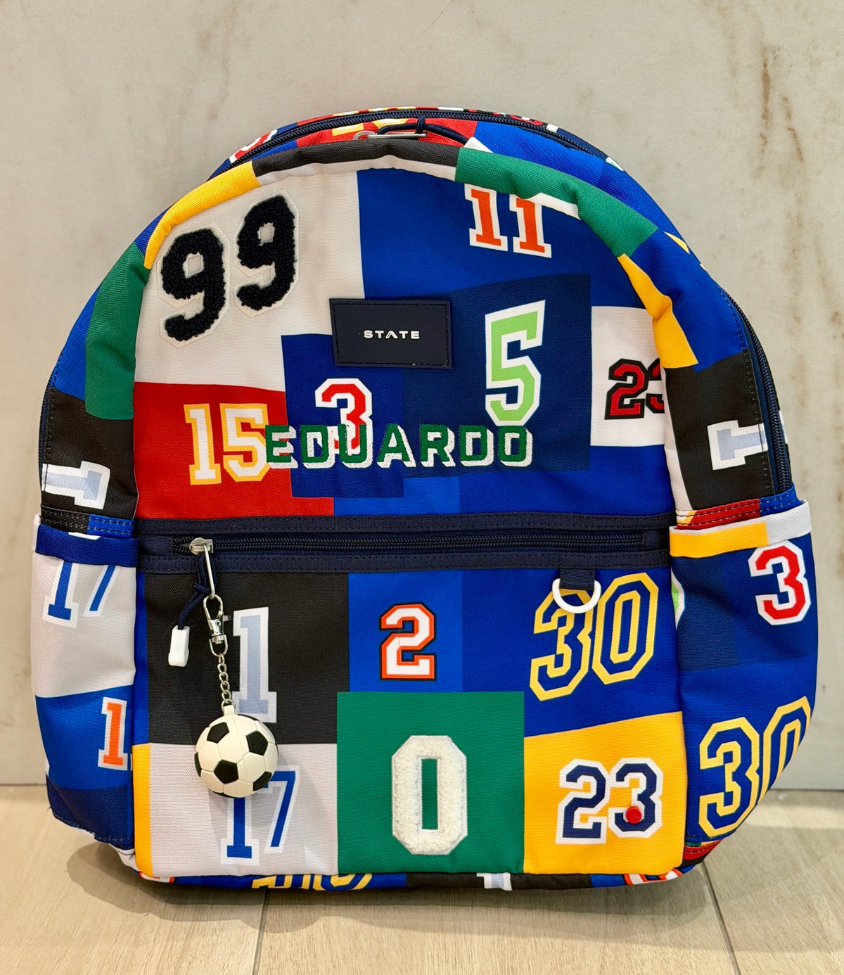 Sports numbers print kids backpack with a soccer ball charm and the name Eduardo custom embroidered in green letters
